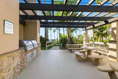 a patio with a grill and picnic tables and benches at Beachfront Resort-sunset views deck & luxe king in Oceanside
