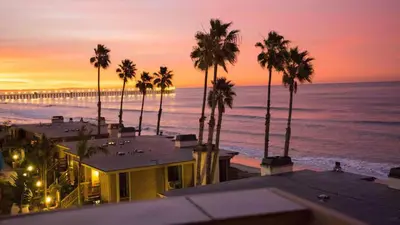 a view of a beach with palm trees and the ocean at Beachfront Resort-sunset views deck & luxe king in Oceanside