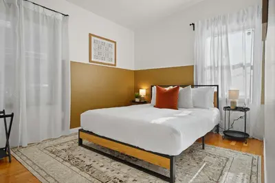 a bedroom with a large bed with white sheets and orange pillows at Stylish Retreat Near Mission Bay with Games & Firepit in San Diego