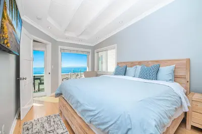 a bedroom with a bed and a view of the ocean at 3Br Oceanfront Home W Balcony Right Over The Sand By Beachview Rentals in Newport Beach