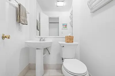 a white bathroom with a toilet and a sink at 4Br Home, One House From Balboa Beach W Rooftop Deck By Beachview Rentals in Newport Beach