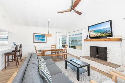 a living room with a couch and a fireplace at Bayfront 3Br With Harbor Views, Only Steps To The Beach By Beachview Rentals in Newport Beach