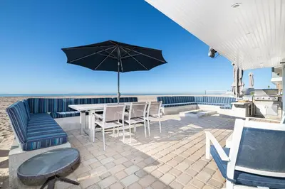 a patio with a table and chairs and an umbrella at 3Br Oceanfront Home W Patio Right On The Sand By Beachview Rentals in Newport Beach