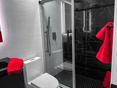a bathroom with a shower and a toilet with red towels at Luxury 3BR, 2BA Newly Renovated with Huge Backyard in San Diego