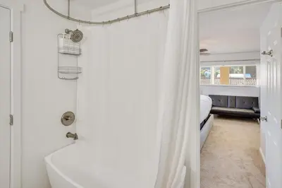 a white bathroom with a shower and a bed at Waterfront Getaway on Lake Elsinore with Swim Spa in Lake Elsinore