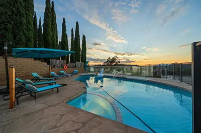 a large swimming pool with chairs and an umbrella at Entire Private Home with 4 Bedrooms 2 Bathrooms, Pool, View, 4 Parking, King Bed, Big Yard, Available Now in El Cajon