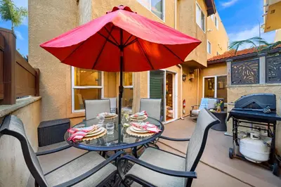 a table with a red umbrella on a patio at Steps to Sand - Pacific Beach 3BR Townhome in San Diego