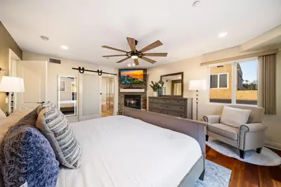 a bedroom with a large white bed and a chair at Steps to Sand - Pacific Beach 3BR Townhome in San Diego