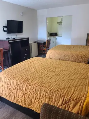 a hotel room with two beds and a desk at Relax Inn And Suites in El Cajon