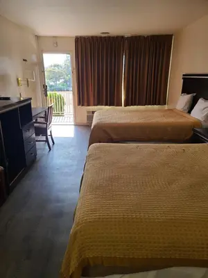 a hotel room with two beds and a desk at Relax Inn And Suites in El Cajon