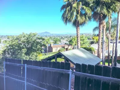 a fence in front of a house with palm trees at Stylish Relaxation-Panoramic Views-Private OASIS in El Cajon