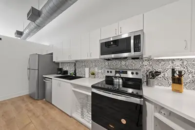 a kitchen with white cabinets and a stove top oven at Party in Gaslamp 4BR Downtown Pad with Bathtub in San Diego