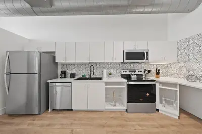 a kitchen with white cabinets and a stainless steel refrigerator at Party in Gaslamp 4BR Downtown Pad with Bathtub in San Diego