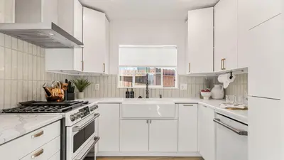 a white kitchen with white cabinets and a stove at Hot Tub • BBQ Island • Outdoor Living • Near San Diego Beaches Glidden Glow by AvantStay in San Diego