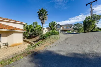 an empty street in front of a house with a palm tree at Private Hilltop Getaway with Patio Dogs Welcome! in Vista