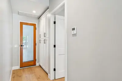 a hallway with white walls and a wooden door at Walk to Pier and Downtown San Clemente Rooftop Deck in San Clemente