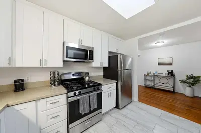 a kitchen with white cabinets and a stove and refrigerator at 3BR Modern Chula Vista Home with Hot Tub and Game Room in Chula Vista