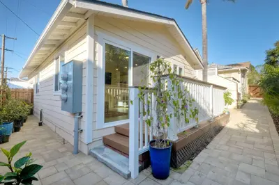 a small white house with a porch and a potted plant at Monarch Cove - Unit C For 4ppl in Oceanside