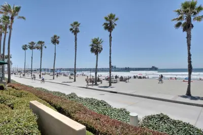 a beach with palm trees and people walking on a sidewalk at Monarch Cove - Unit C For 4ppl in Oceanside