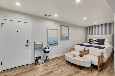 a bedroom with a king sized bed and a chair at ON Avenida Del Mar Heart of Downtown 10 minute WALK to the Pier Parking in San Clemente