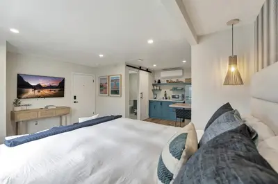 a bedroom with a large white bed and a kitchen at ON Avenida Del Mar Heart of Downtown 10 minute WALK to the Pier Parking in San Clemente