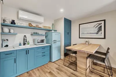 a kitchen with blue cabinets and a wooden table at ON Avenida Del Mar Heart of Downtown 10 minute WALK to the Pier Parking in San Clemente