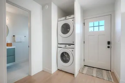 a laundry room with a washer and dryer next to a door at Modern Ocean-View Retreat w/ Firepit & Steps to Carlsbad Beach in Carlsbad
