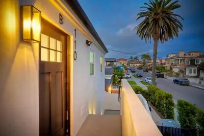 a balcony with a door and a palm tree at Modern Ocean-View Retreat w/ Firepit & Steps to Carlsbad Beach in Carlsbad