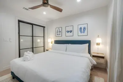 a bedroom with a white bed and a ceiling fan at Sycamore Haus Estate – Rent All 3 Ocean-View Luxury Condos Steps from Carlsbad State Beach in Carlsbad