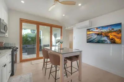 a kitchen with a dining room table and a painting on the wall at Luxury Carlsbad Retreat | Across The Street From Beach | Firepit, BBQ, Ping Pong, Cornhole & More in Carlsbad
