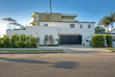 a white house with a garage on a street at Luxury Carlsbad Retreat | Across The Street From Beach | Firepit, BBQ, Ping Pong, Cornhole & More in Carlsbad