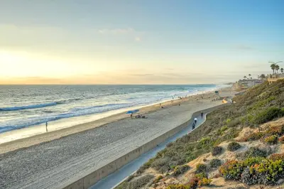 a beach with people walking on the sand and the ocean at Luxury Carlsbad Retreat | Across The Street From Beach | Firepit, BBQ, Ping Pong, Cornhole & More in Carlsbad