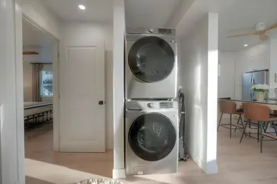 a washer and dryer in a living room at Luxury Carlsbad Retreat | Across The Street From Beach | Firepit, BBQ, Ping Pong, Cornhole & More in Carlsbad