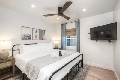 a bedroom with a large bed with a ceiling fan at Modern Carlsbad Vacation Rental with Ocean Views, Private Patio, Fire Pit & Walkable Location in Carlsbad