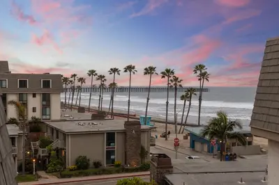 a view of the beach with palm trees and condos at Stunning Oceanview Penthouse | 2BR, Sleeps 6 | North Coast Village Resort in Oceanside
