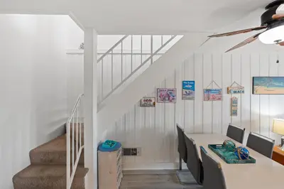 a dining room with a table and a staircase at Stunning Oceanview Penthouse | 2BR, Sleeps 6 | North Coast Village Resort in Oceanside