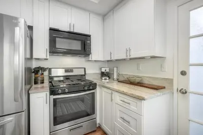 a kitchen with white cabinets and a stove and microwave at Carlsbad Coastal Cottage — Private Patio + Gated Pool & Spa in Minutes to the Beach! in Carlsbad