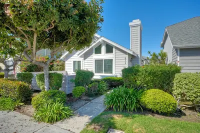 a white house with bushes in front of it at Carlsbad Coastal Cottage — Private Patio + Gated Pool & Spa in Minutes to the Beach! in Carlsbad