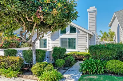 a white house with a tree and bushes at Carlsbad Coastal Cottage — Private Patio + Gated Pool & Spa in Minutes to the Beach! in Carlsbad