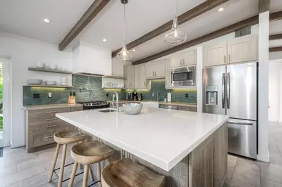 a kitchen with a large white counter and stools at Luxury 3-Bed Beach Cottage with Hot Tub, Fire Pit, BBQ - Walk To Beach in Cardiff-by-the-Sea