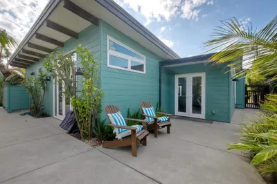 a blue house with two chairs and a table at Luxury 3-Bed Beach Cottage with Hot Tub, Fire Pit, BBQ - Walk To Beach in Cardiff-by-the-Sea