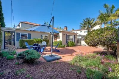 a house with a patio with a table and an umbrella at Coastal Cottage Steps from the Sand | Walk to Carlsbad Village, Dog-Friendly in Carlsbad
