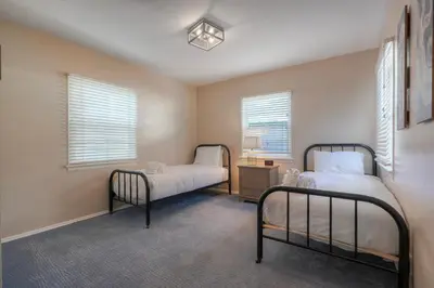two beds in a room with two windows at Coastal Cottage Steps from the Sand | Walk to Carlsbad Village, Dog-Friendly in Carlsbad