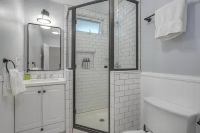 a white bathroom with a shower and a sink at Coastal Cottage Steps from the Sand | Walk to Carlsbad Village, Dog-Friendly in Carlsbad