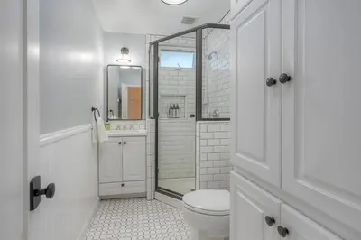 a white bathroom with a toilet and a shower at Coastal Cottage Steps from the Sand | Walk to Carlsbad Village, Dog-Friendly in Carlsbad