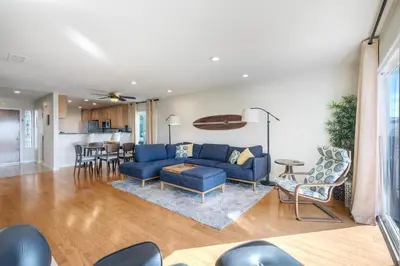 a living room with a blue couch and a kitchen at Luxury Coastal Escape | Sleeps 4 | Ocean Views + Resort Amenities in Carlsbad