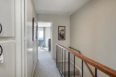 a hallway with white walls and a stairway at Luxury Coastal Escape | Sleeps 4 | Ocean Views + Resort Amenities in Carlsbad