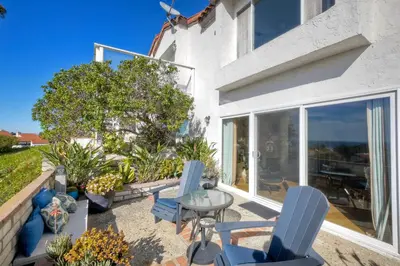 a patio with blue chairs and a glass table at Luxury Coastal Escape | Sleeps 4 | Ocean Views + Resort Amenities in Carlsbad