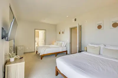 a white bedroom with two beds and a tv at By Seaport Village and Navy Base! Chic Condo with Pool in National City
