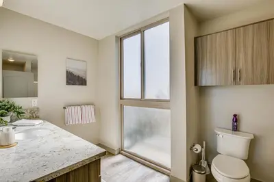 a bathroom with a sink and a toilet and a window at By Seaport Village and Navy Base! Chic Condo with Pool in National City